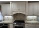 Kitchen featuring gas range, granite countertops, and custom vent hood with white cabinets at 211 Hillcrest Dr, Oxford, NC 27565