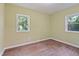 Empty bedroom featuring neutral paint, wood-look floors, and bright natural light from two windows at 3863 Avents Ferry Rd, Sanford, NC 27330