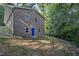 Back view of brick home with a bright blue door and partially terraced landscaping at 3863 Avents Ferry Rd, Sanford, NC 27330