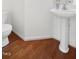 Simple powder room featuring hardwood floors, toilet, and pedestal sink at 428 Grand Pointe Dr, Garner, NC 27529