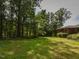 Lush green backyard with mature trees surrounding a single-story brick home at 4324 Garland Dr, Raleigh, NC 27606