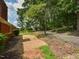 Side yard featuring a brick home, gravel area, and views of the driveway and surrounding trees at 4324 Garland Dr, Raleigh, NC 27606
