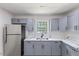 Beautiful kitchen with grey cabinets, stainless steel refrigerator and marbled countertops at 1020 Benning St, Durham, NC 27703