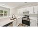 Bright kitchen featuring white cabinets, stainless steel appliances, and bar top seating at 137 Cricketgrass Dr, Cary, NC 27513