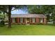 Charming brick home with a metal roof, complemented by a lush green lawn and mature trees at 516 Ivey Rd, Graham, NC 27253