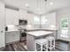 Bright kitchen with stainless steel appliances, gray cabinets, and island with bar stool seating at 5215 Goshawk Ln, Graham, NC 27253