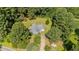 An aerial view of a blue house surrounded by mature trees, a large yard, and a long dirt driveway at 545 Barnette Rd, Louisburg, NC 27549