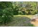 View of a well-maintained backyard featuring green grass, mature trees, and the corner of a home at 545 Barnette Rd, Louisburg, NC 27549