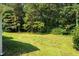 View of the backyard with lush green grass, mature trees, and the side of a house at 545 Barnette Rd, Louisburg, NC 27549