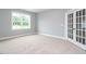 Cozy room with carpet floors and a large window showcasing natural light, complemented by stylish french doors at 1221 Barreto Dr, Wendell, NC 27591