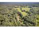 Aerial view of a property nestled within a lush, tree-filled landscape and open meadow at 133 Acorn Ln, Pittsboro, NC 27312