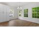 Well-lit dining room with wood-look floors, white walls, and multiple windows offering views of lush greenery at 1408 South St, Durham, NC 27707