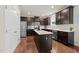 Well-lit kitchen featuring stainless steel appliances, dark cabinets, an island, and hardwood floors at 4014 White Kestrel Dr, Raleigh, NC 27616