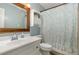 Cozy bathroom featuring a white vanity, wood-trimmed mirror, and shower with leaf-patterned curtain at 5840 Fayetteville Rd, Raleigh, NC 27603