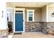 Close up of blue front door with stone trim and white accents and verdant landscaping at 812 Teal Lake Dr, Holly Springs, NC 27540