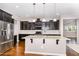 This is a kitchen with stainless steel appliances, a large island, and dark cabinetry at 812 Teal Lake Dr, Holly Springs, NC 27540