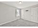 Simple bedroom featuring gray carpet, a window with curtains, and a white door at 104 Roscommon Ln, Clayton, NC 27520