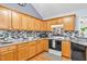 Well-lit kitchen with wooden cabinets, modern appliances, and granite countertops and stylish backsplash at 104 Roscommon Ln, Clayton, NC 27520