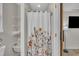 Bathroom with a floral-themed shower curtain and open shelving, creating a functional design at 2003 Zbonack Ct, Creedmoor, NC 27522