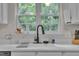 Close-up of a kitchen sink with modern faucet, white countertops, and a bright view from the window at 2003 Zbonack Ct, Creedmoor, NC 27522