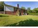 Brick home's expansive backyard, featuring a chimney, sliding glass doors, and partial driveway view at 3603 Grimes Ave, Durham, NC 27703