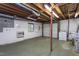 Unfinished basement with exposed wood beams, utility fixtures, and a garage door at 3603 Grimes Ave, Durham, NC 27703