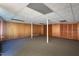 Unfinished basement with wood paneling, support beams, and neutral-toned carpet at 3603 Grimes Ave, Durham, NC 27703