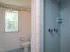 Bathroom with blue tile shower, yellow floral wallpaper, and a window offering natural light at 3603 Grimes Ave, Durham, NC 27703