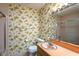 Retro bathroom showcasing vintage floral wallpaper, a peach countertop, and tiled flooring at 3603 Grimes Ave, Durham, NC 27703