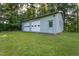 A detached garage with two bays and a side entry door sits on a well-maintained grassy lot surrounded by trees at 3603 Grimes Ave, Durham, NC 27703