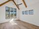 Bedroom with high ceilings, exposed wooden beams, hardwood floors, and three large windows at 104 Birdie Court, Pittsboro, NC 27312