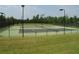 View of multiple tennis courts with lighting, surrounded by green space and a black chain-link fence at 104 Birdie Court, Pittsboro, NC 27312