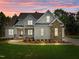 Charming two-story home with a combination of stone and vinyl siding, complimented by a colorful sunset backdrop at 6633 Prescott Shore Dr, Wake Forest, NC 27587