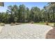 Expansive backyard featuring a large paved patio area, lush lawn, and natural landscaping with mature trees at 213 Westhampton Dr, Pittsboro, NC 27312
