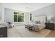 Bright primary bedroom features neutral tones, a ceiling fan, and large window for natural light and a seating area at 213 Westhampton Dr, Pittsboro, NC 27312