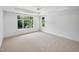 Bright bedroom with neutral carpet, trey ceiling, ceiling fan, and large windows offering wooded views at 213 Westhampton Dr, Pittsboro, NC 27312