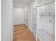 Bright hallway featuring hardwood floors, closet doors, and a laundry area with storage cabinets at 213 Westhampton Dr, Pittsboro, NC 27312