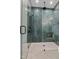 Detailed view of a glass shower with dark green vertical tile, matte black hardware, and a tiled shower floor at 213 Westhampton Dr, Pittsboro, NC 27312