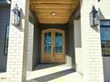 Grand entryway with a double-door entry, brick pillars, and dark trim on a new construction home at 3812 Peaceful Creek Trl, Zebulon, NC 27597