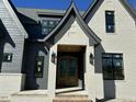 Close up of a beautiful new construction home with an elegant, light-colored brick and dark trim around the entryway at 3812 Peaceful Creek Trl, Zebulon, NC 27597