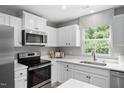 Bright kitchen featuring white cabinets, stainless steel appliances, and a window over the sink at 164 Clove Hitch Ln, Fuquay Varina, NC 27526