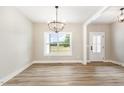 Bright dining room featuring wood floors, a modern chandelier, and a large window offering scenic views at 7327 Shawan Rd, Wendell, NC 27591
