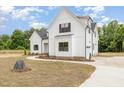 Elegant white farmhouse exterior with a curved driveway, beautiful landscaping, and charming architectural details at 7327 Shawan Rd, Wendell, NC 27591