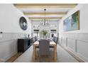 Formal dining room with modern chandelier, wood-beam ceiling and accent wainscoting at 5305 Dixon Dr, Raleigh, NC 27609