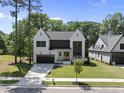 Stunning modern home showcasing black trim, a paved driveway, and lush green grass at 5305 Dixon Dr, Raleigh, NC 27609