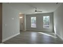 Bright living room features neutral walls, wood floors, ceiling fan, and natural light from large windows at 492 Traditions Grande Blvd # 26, Wake Forest, NC 27587