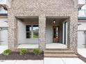 Inviting entrance featuring a brick-columned porch and a stylish wood front door at 804 Ambercrest Place, Durham, NC 27705