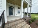 Inviting front porch with brick steps, black iron railings, and a view of the manicured lawn at 123 Sage Ln # 010, Four Oaks, NC 27524