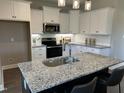 Modern kitchen with granite counters, stainless appliances, white cabinets, and a large kitchen island at 98 Prency Ln, Middlesex, NC 27557