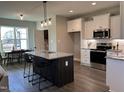 Open kitchen boasts a center island with seating, modern stainless appliances, and white shaker cabinets at 98 Prency Ln, Middlesex, NC 27557